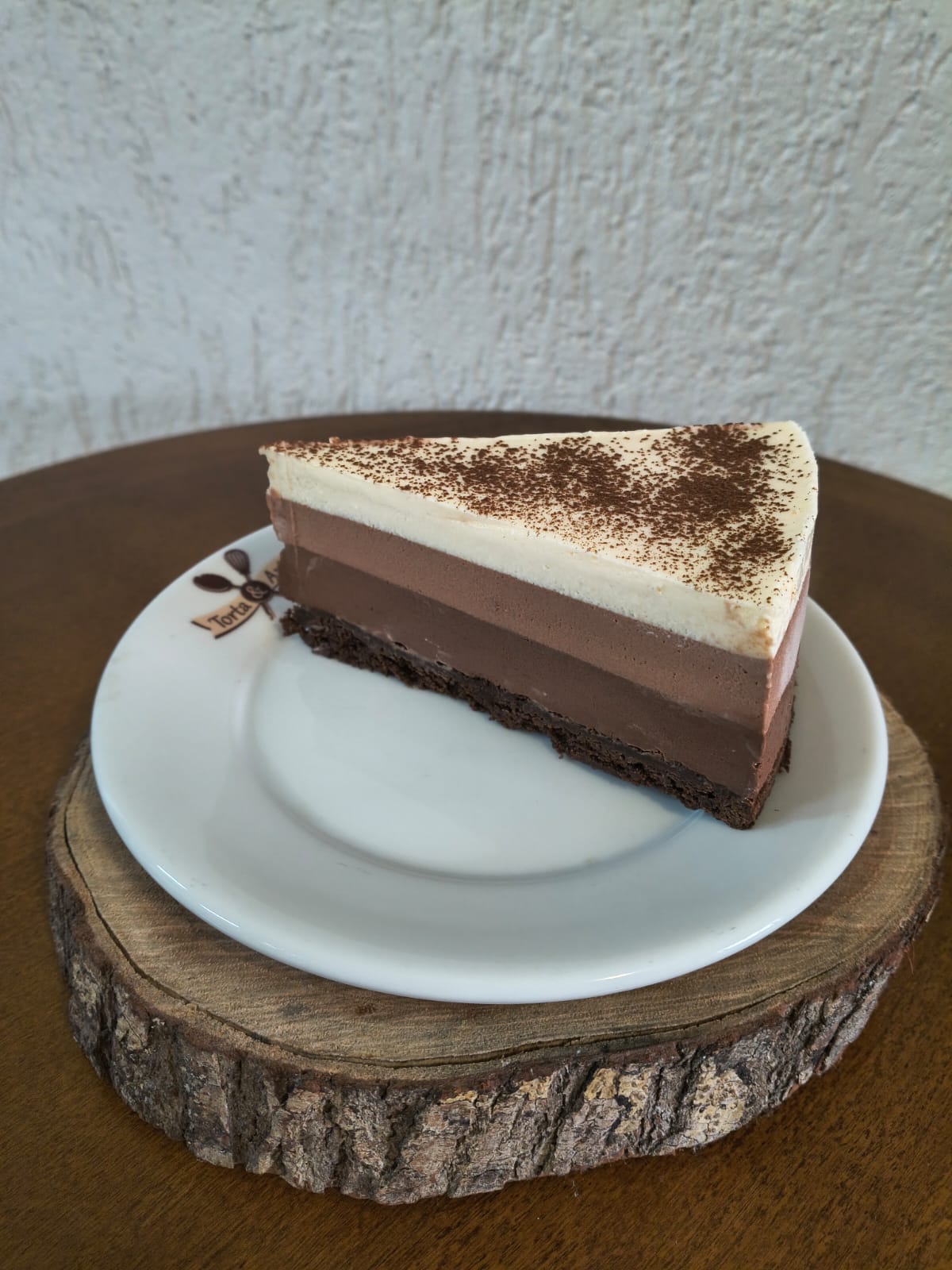 Fatia de mousse de três chocolates da Torta & Arte, com camadas de chocolate ao leite, meio amargo e branco